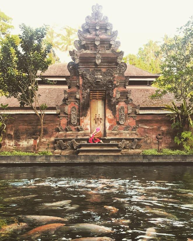 Leigh Bertelsen sitting at a temple doorway in Bali with a koi pond in the foreground