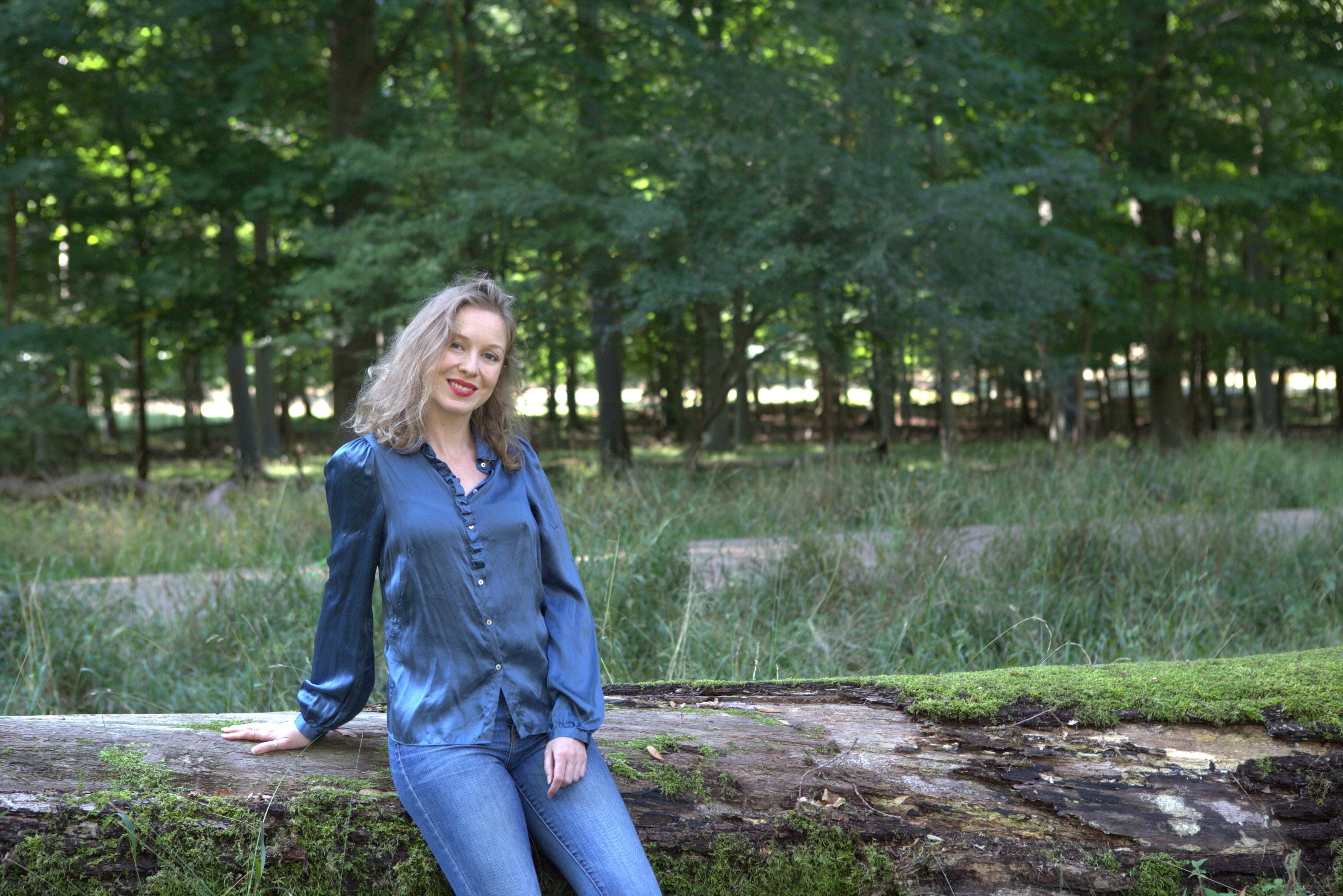 Leigh Bertelsen standing by a mossy log in the forest outside Copenhagen